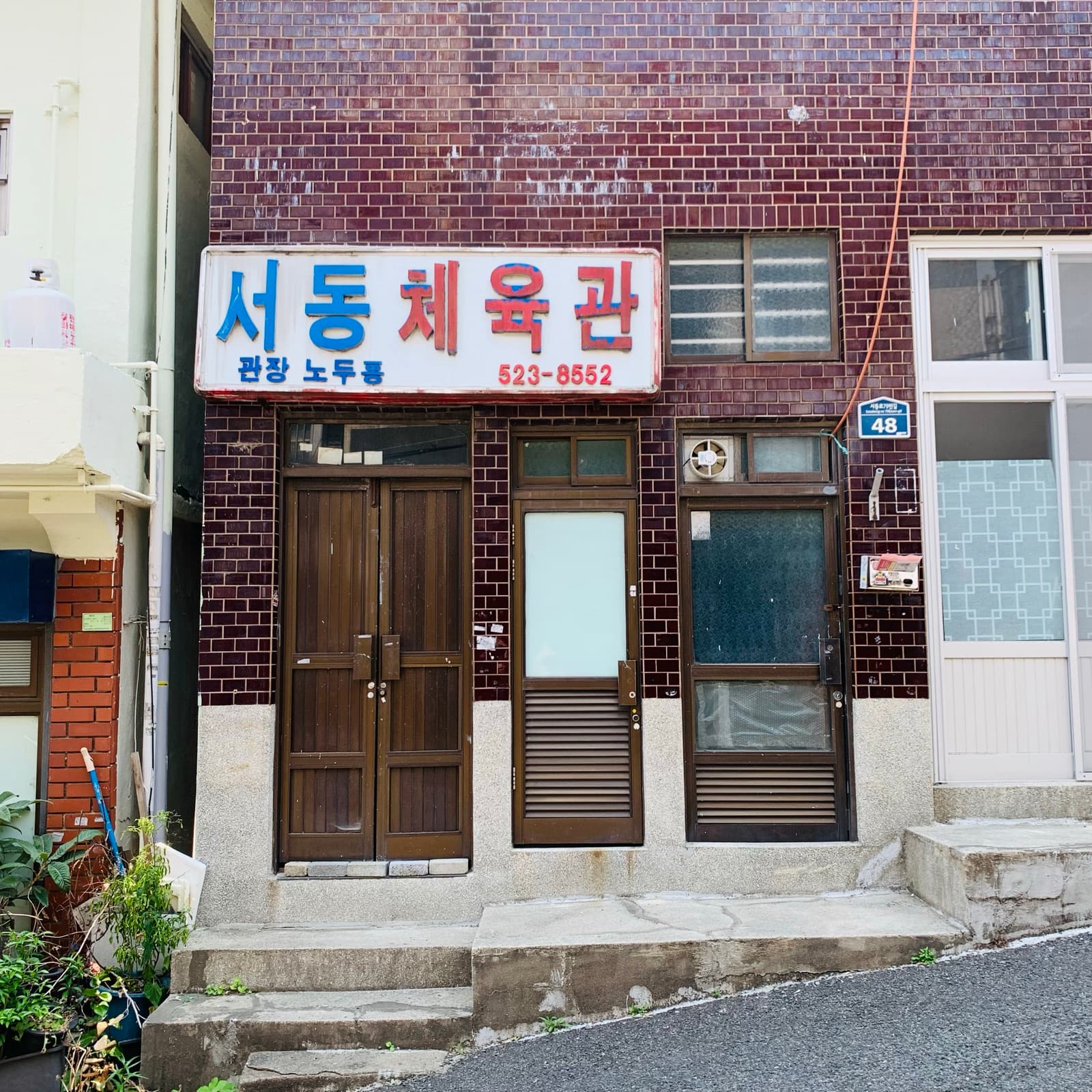 갈색 타일 건물에 붙은 서동체육관 간판과 나무 문.